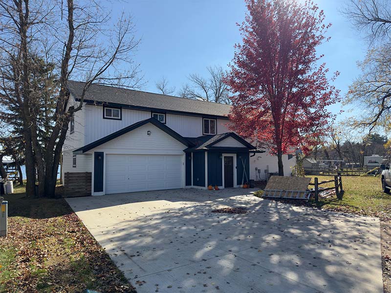 Two-story white Fargo house with dark trim and new roofing after a successful storm damage insurance claim.